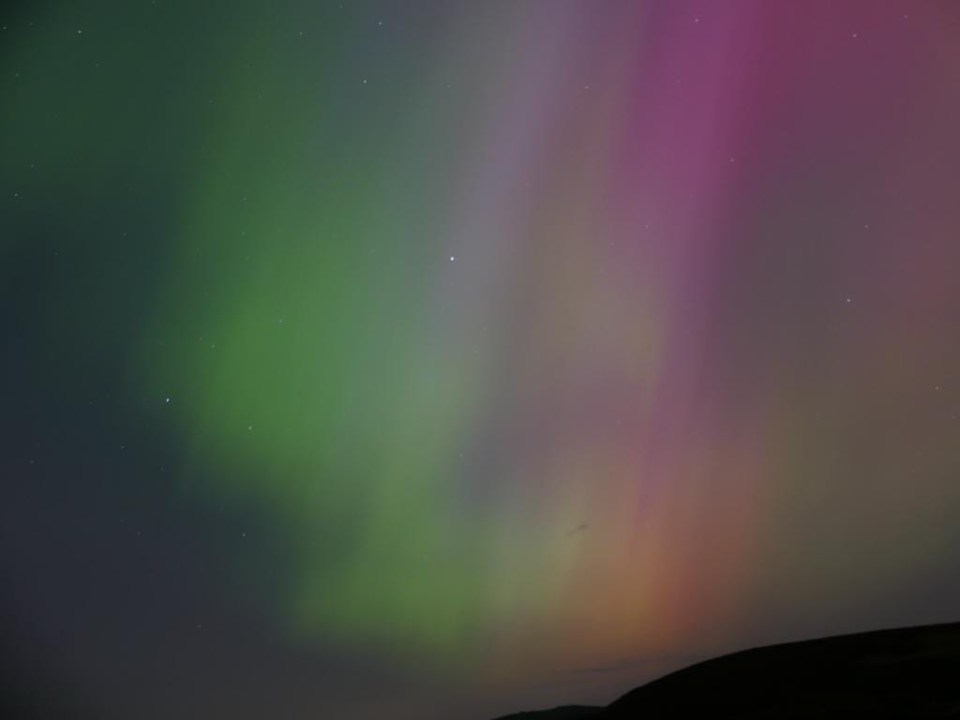 Aurora borealis over a dark landscape.