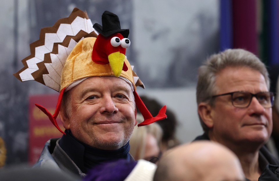 A man wearing a turkey hat smiles at a Christmas Eve meat auction.