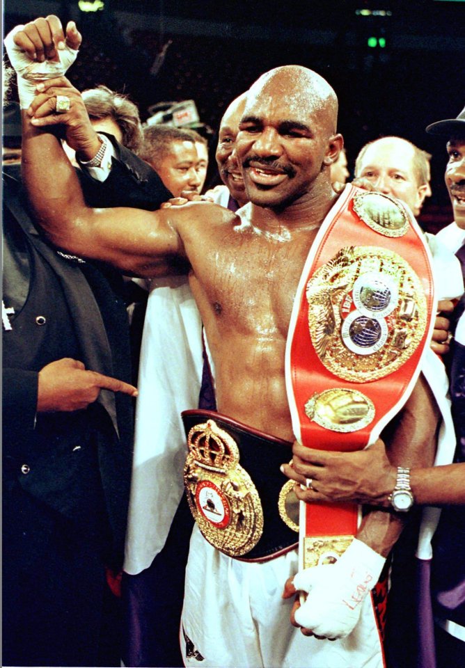 Evander Holyfield holding the WBA and IBF heavyweight championship belts after defeating Michael Moorer.