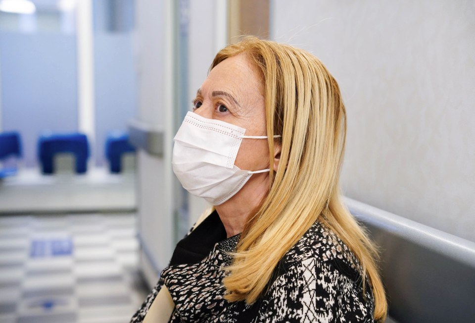 A woman wearing a face mask waits in a hospital waiting room.