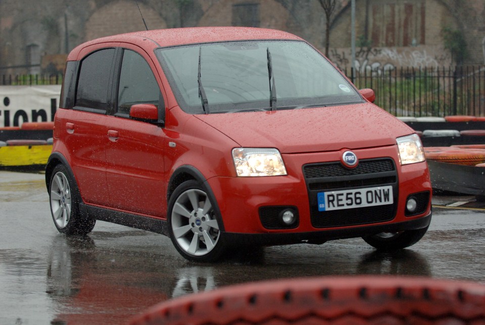 Red Fiat Panda 100HP driving on a wet road.