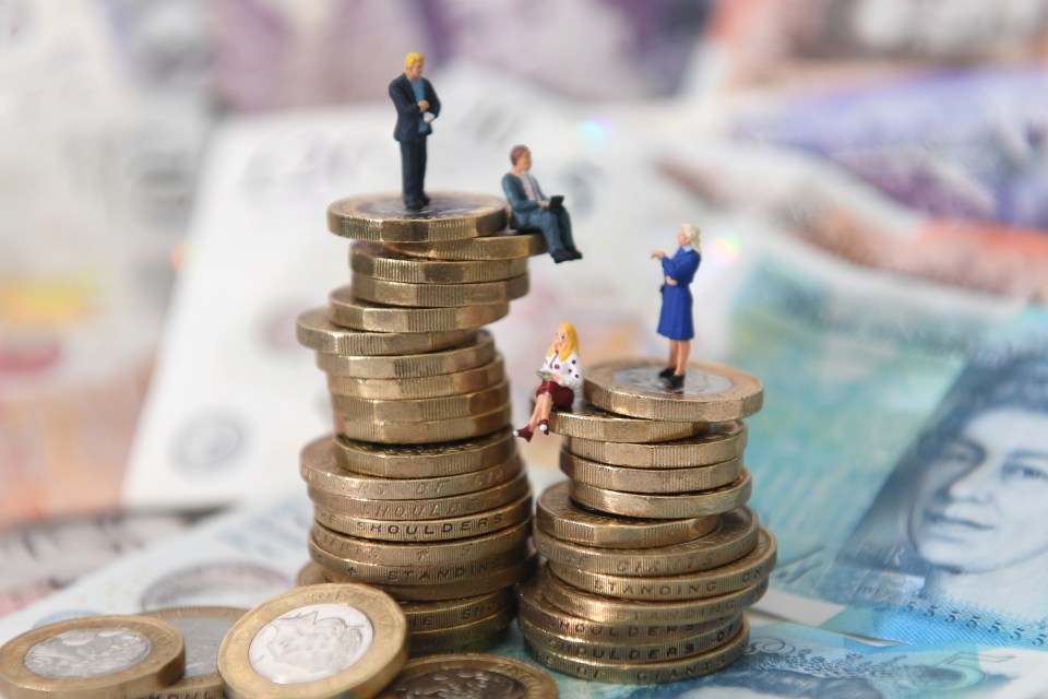 Miniature figures of men and women sitting on stacks of British coins.