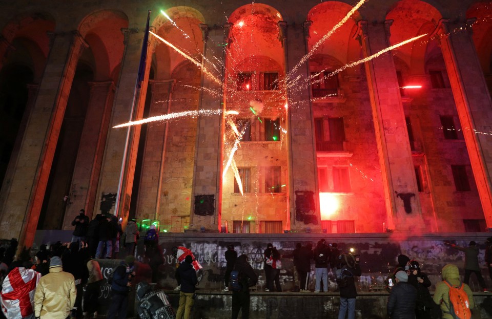 Fireworks explode in front of the parliament building during a protest against the new government’s decision to suspend the European Union talks