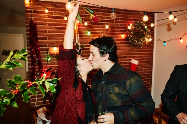 Couple kissing at a holiday party.