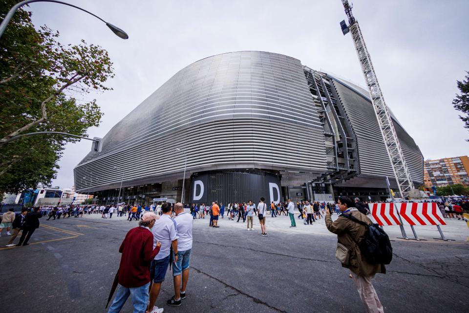 Exterior view of the Estadio Santiago Bernabéu stadium in Madrid, Spain, with fans outside before a Real Madrid game.