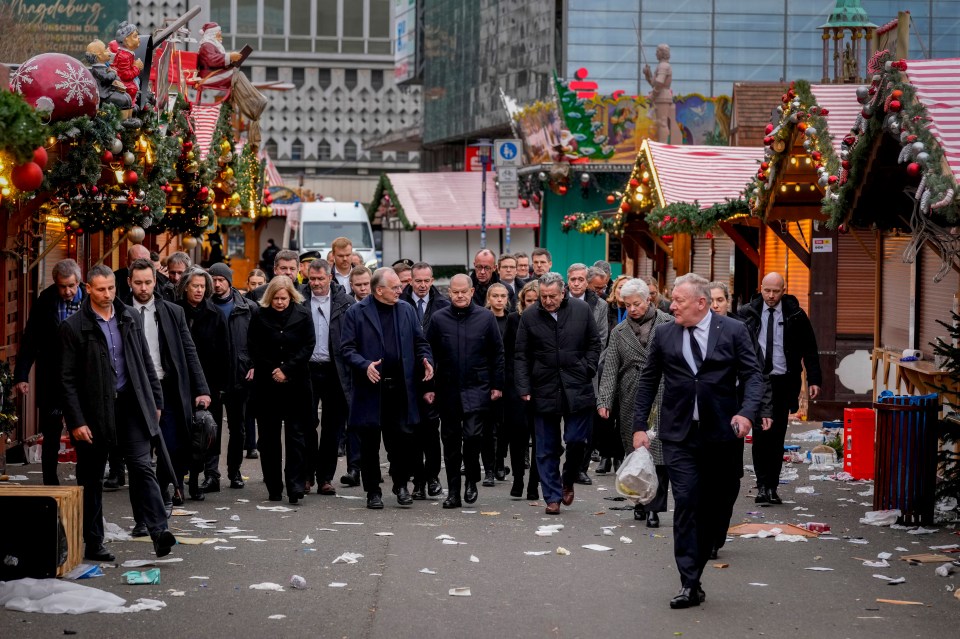 German Chancellor Olaf Scholz, centre, walks through the market following the attack