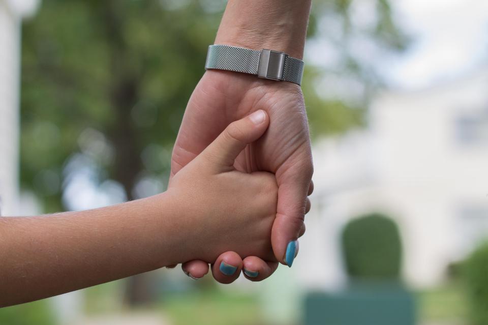 A mother and child holding hands.