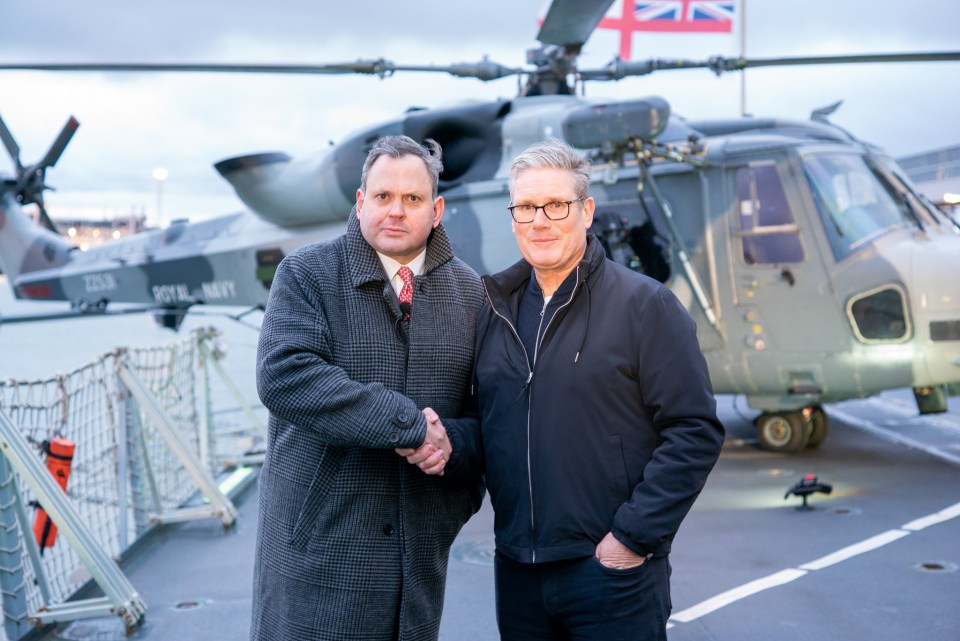 Harry Cole and Keir Starmer shaking hands on a Royal Navy ship in Estonia.