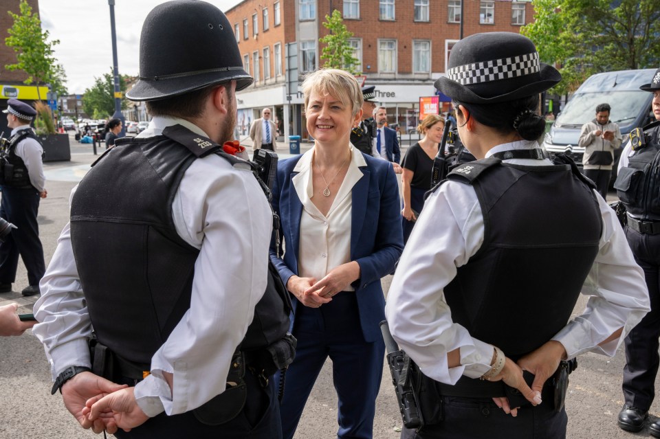 Yvette Cooper, centre, speaks with police officers during a walk through Lewisham town centre