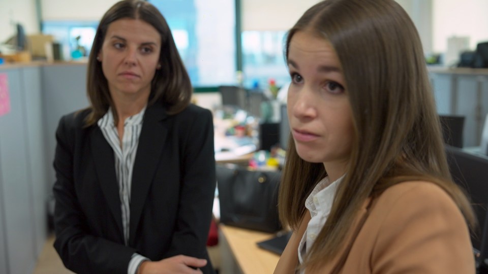 Two women in business attire having a serious conversation.