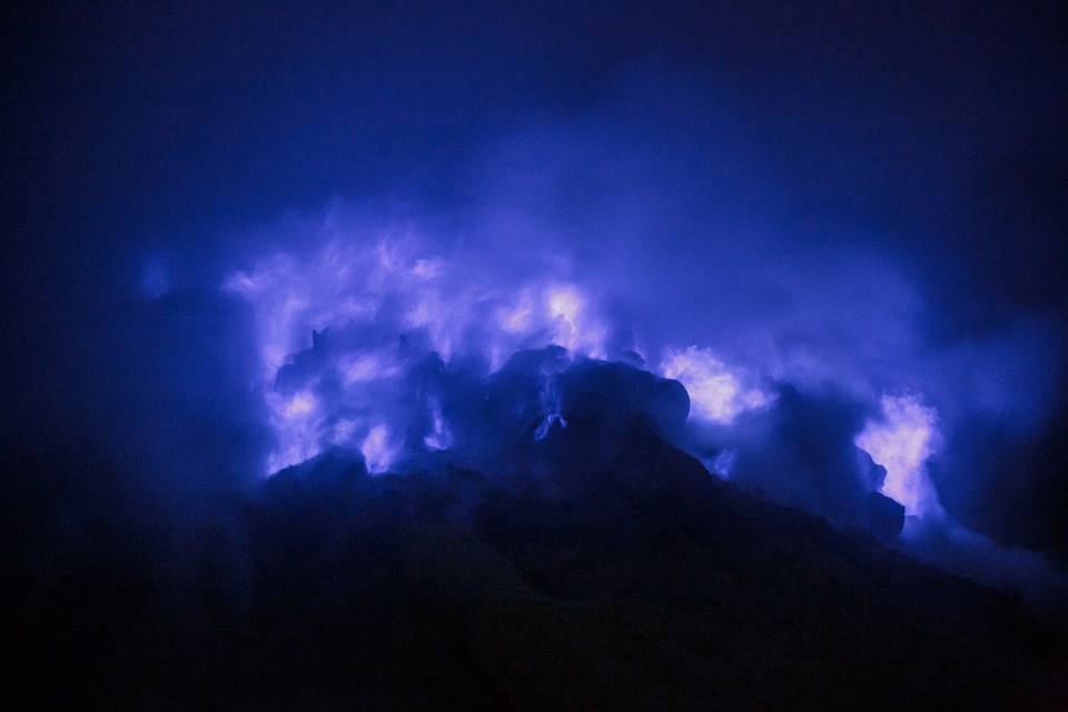 Hot sulphuric gases emerging from the surface of the crater burn an electric blue upon contact with the cold air