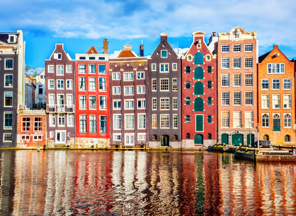 Amsterdam canal houses reflected in water.