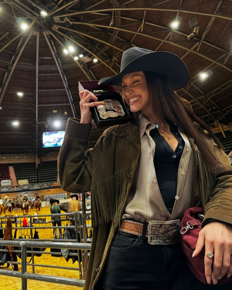 Cowgirl holding her Rookie of the Year award buckle.