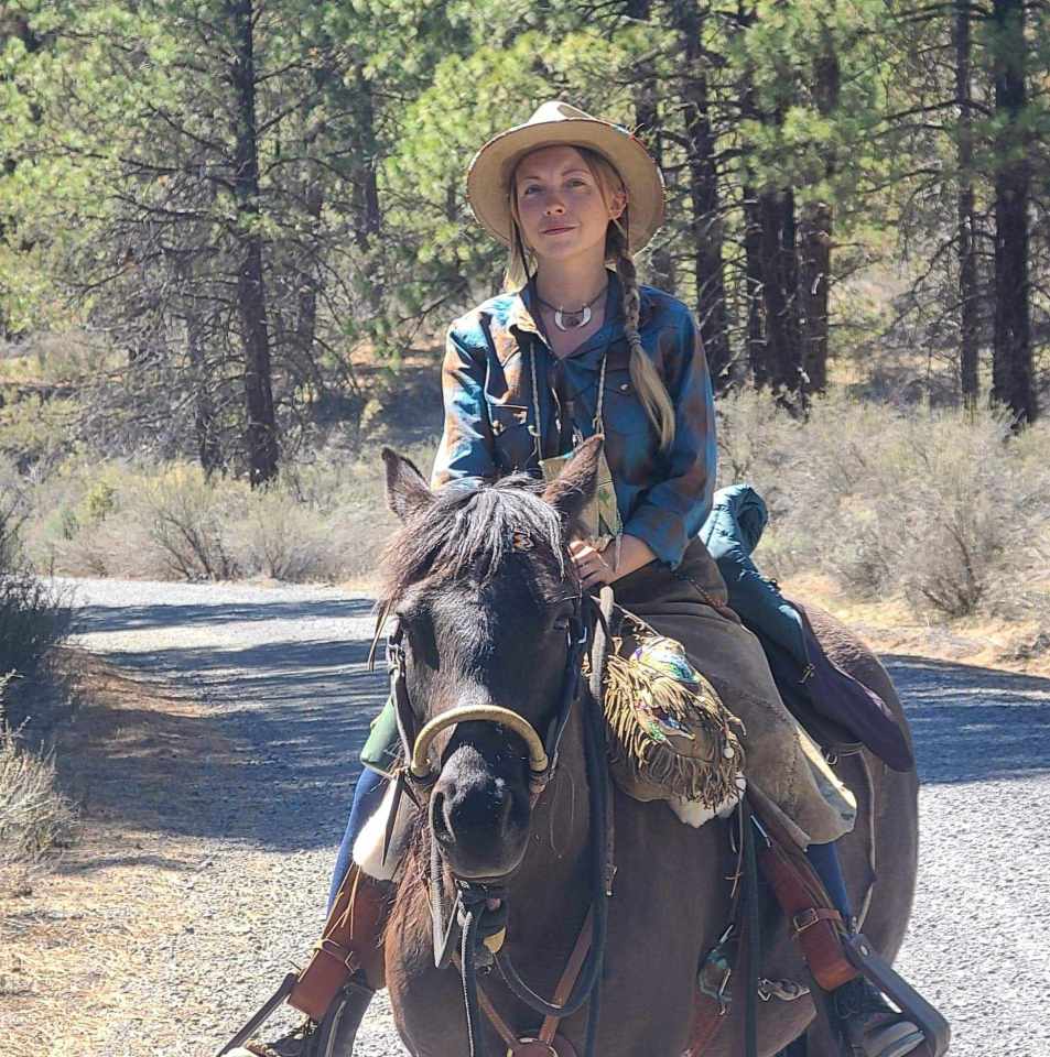 Woman on horseback in a wooded area.