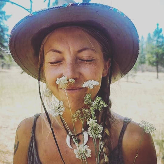 Woman in a hat smelling wildflowers.