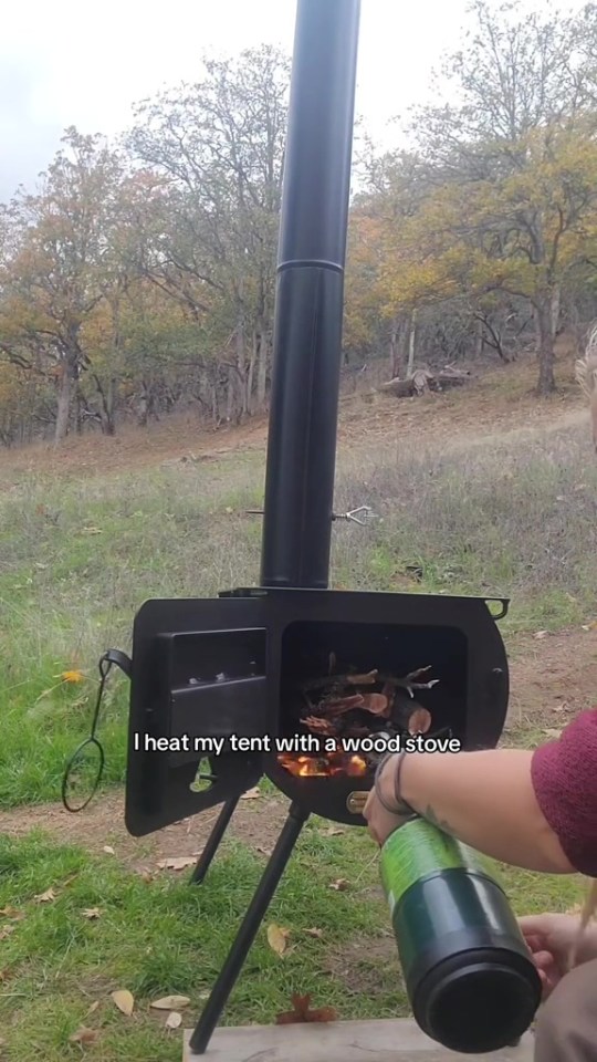 Woman using a wood stove to heat her tent.