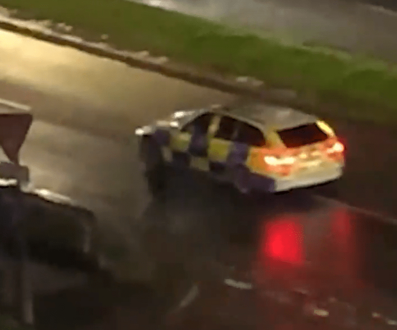 Police car driving on a wet road at night.