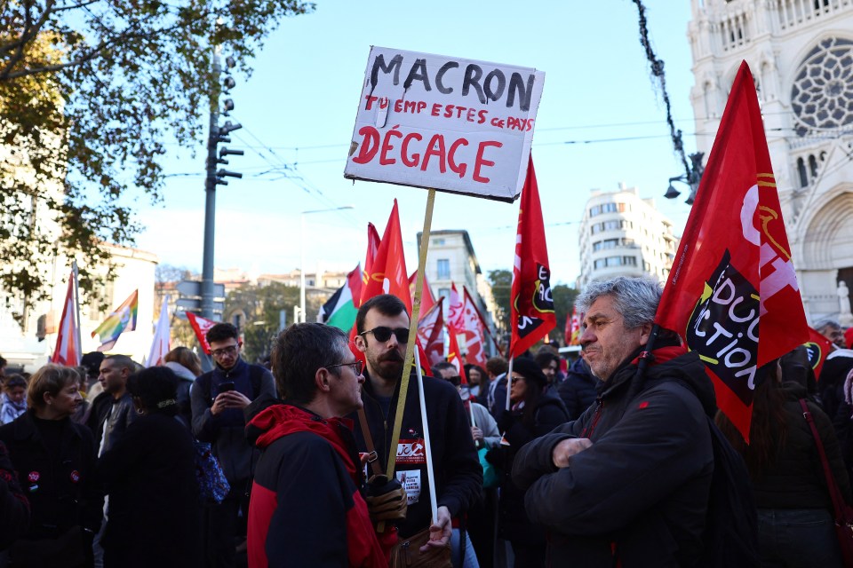 Protests are being held across France today with one demonstrator holding up a placard reading: 'Macron, you stink, get out'