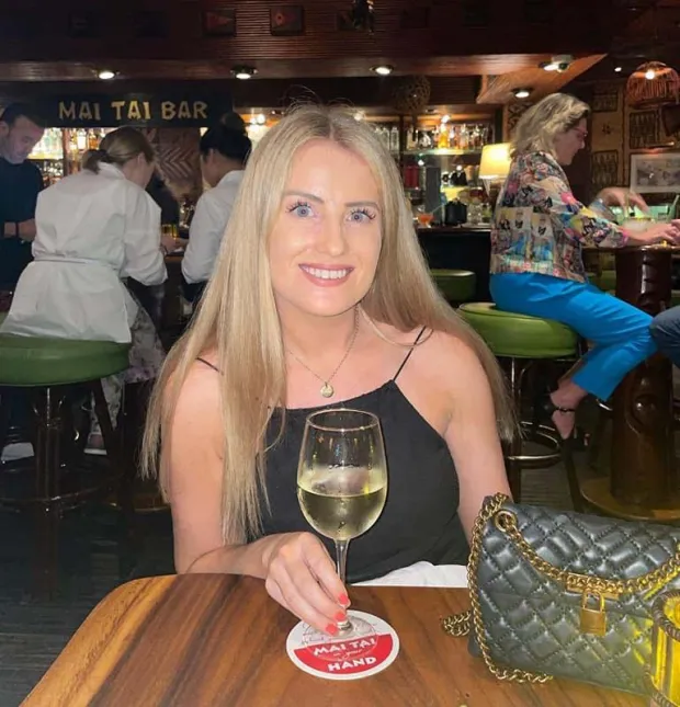 Woman at a Mai Tai bar holding a glass of white wine.