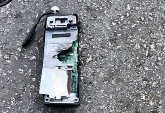 Damaged handheld radio on the ground.