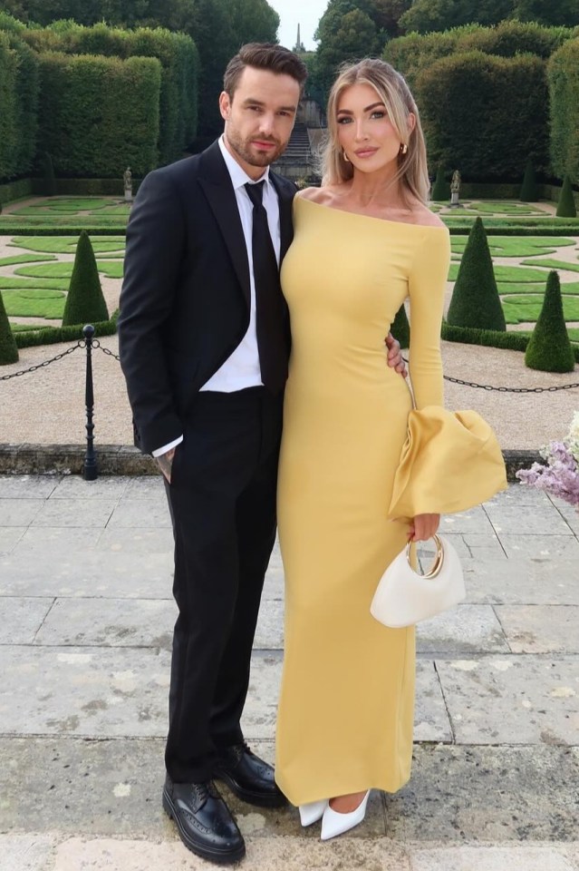 Couple in formal wear posing in a garden.