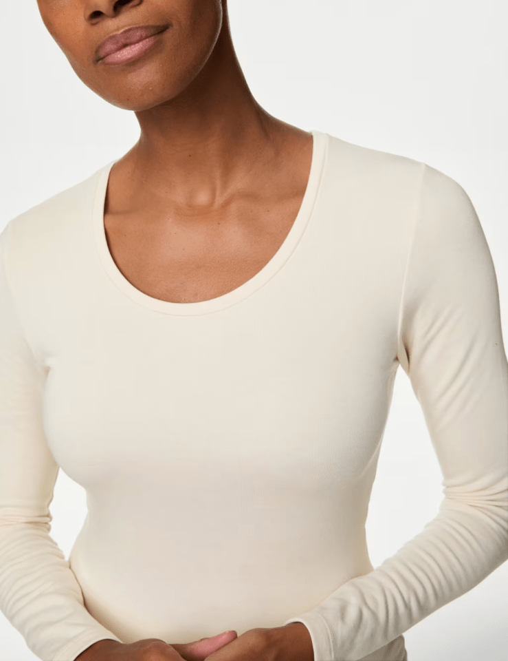 Close-up of a woman's off-white long-sleeved shirt with a round neckline.