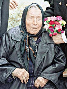 Elderly woman in a black coat holding a bouquet of carnations.