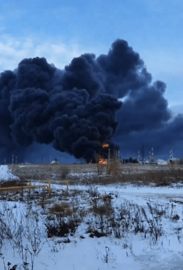 Large plume of black smoke billowing from a fire in a snowy landscape.