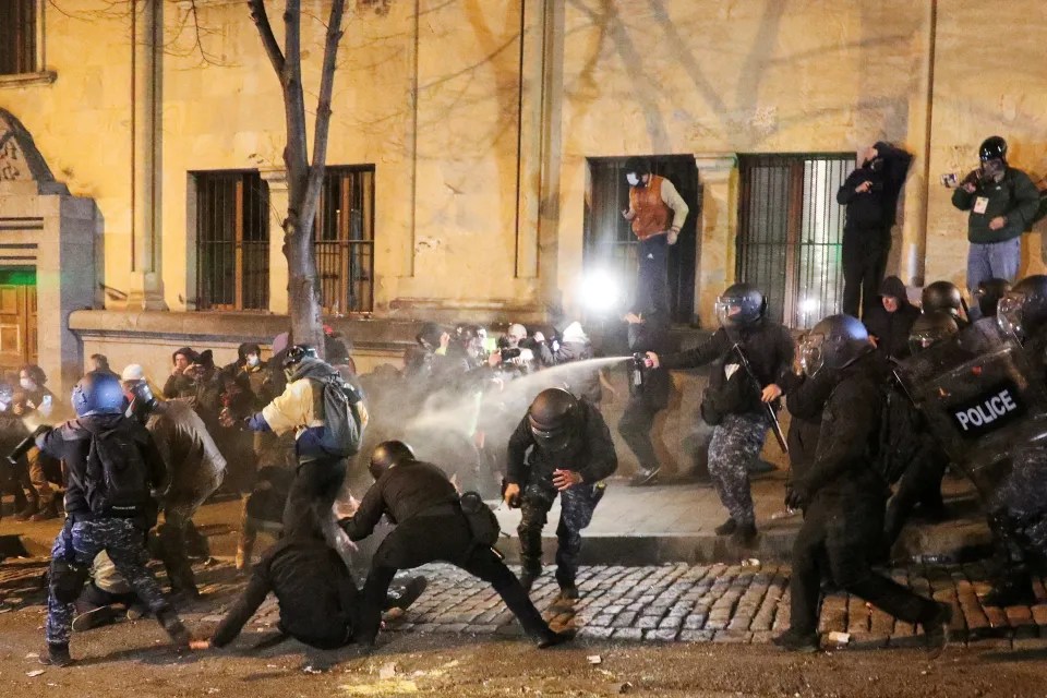 A police officer uses a crowd control spray against protesters in early December