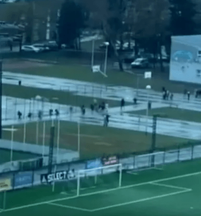 People walking on a snow-covered sports field.