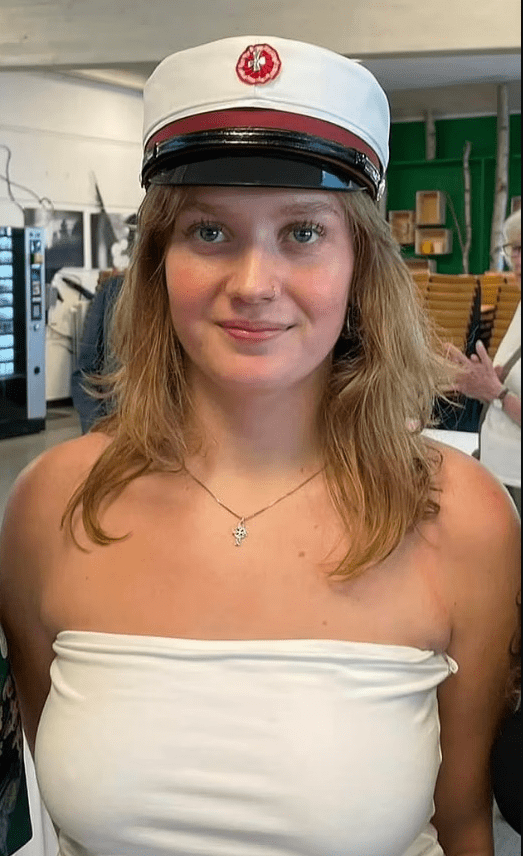 Young woman wearing a white graduation cap and a white tube top.