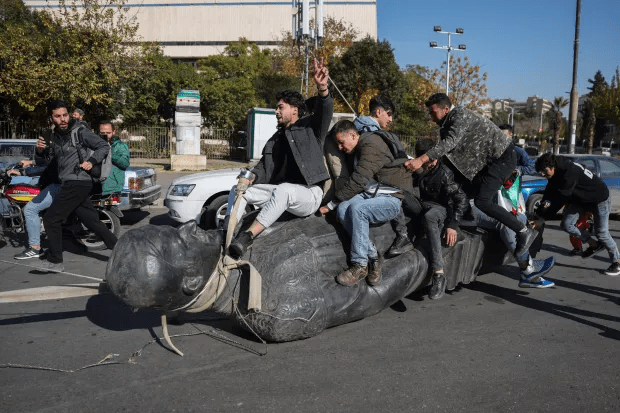 Protesters pulling down a statue in the street.