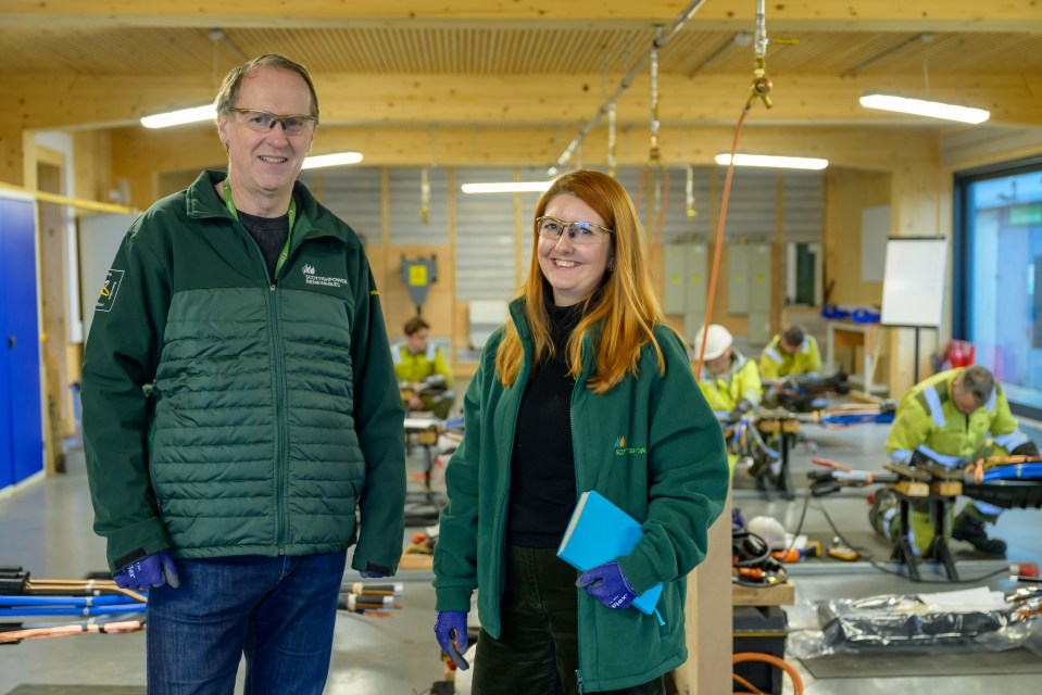 Two people in ScottishPower Renewables jackets stand in a training center.