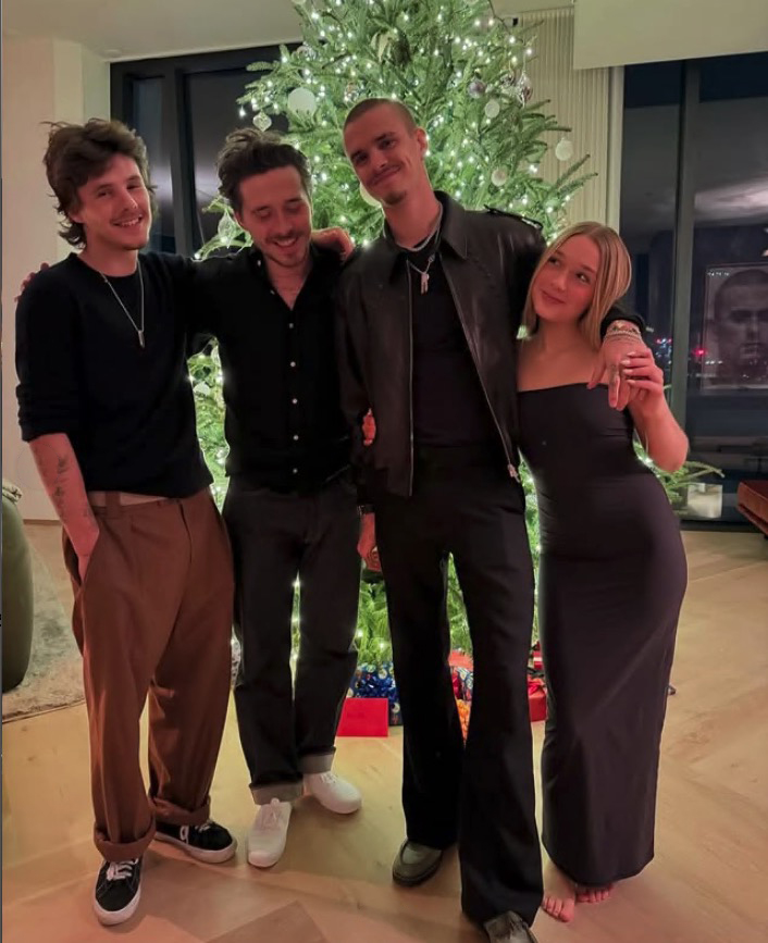 Four young adults posing together by a Christmas tree.