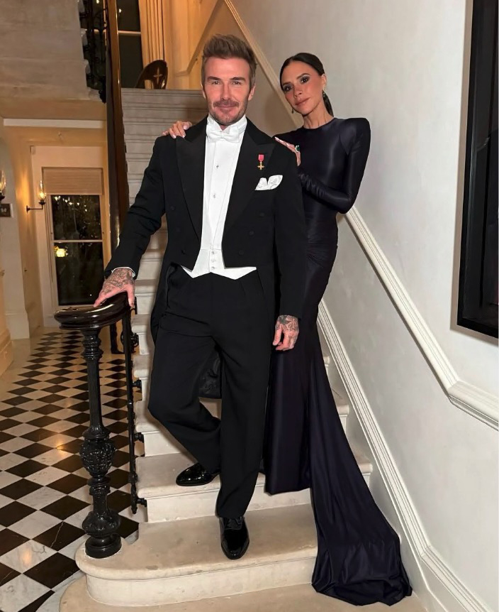 David and Victoria Beckham in formal wear on a staircase.