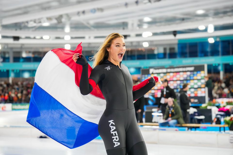 Jutta Leerdam celebrates a victory at the Daikin NK Allround & Sprint, holding the Dutch flag.