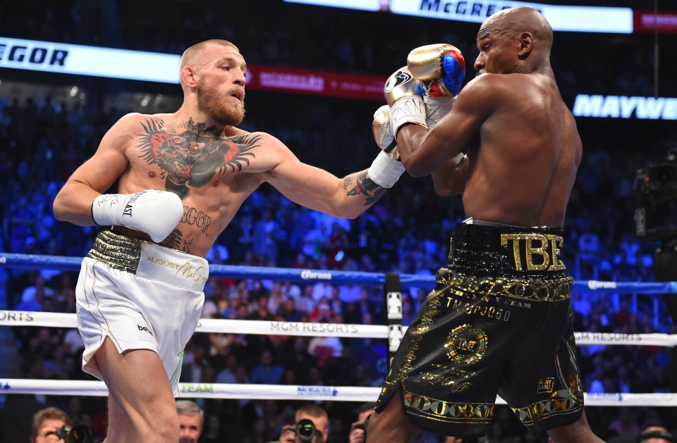 Conor McGregor throwing a punch at Floyd Mayweather Jr. during a boxing match.