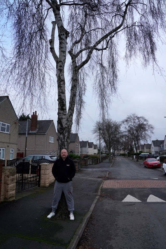 Sean leans against a tree outside his house