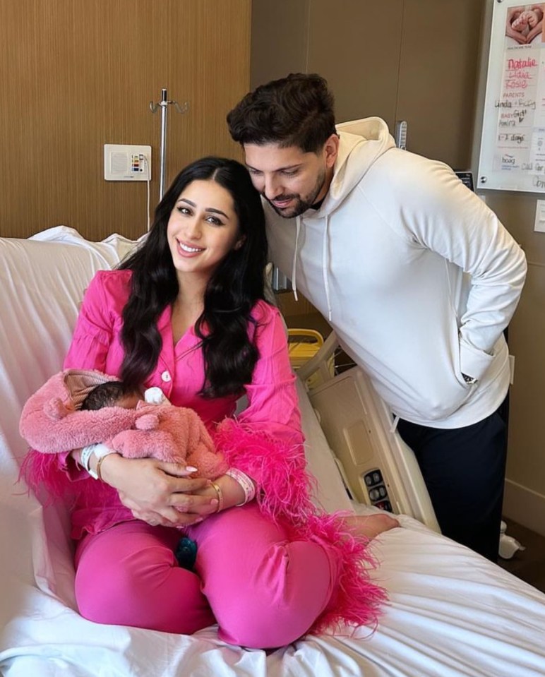 Parents holding their newborn baby in a hospital room.