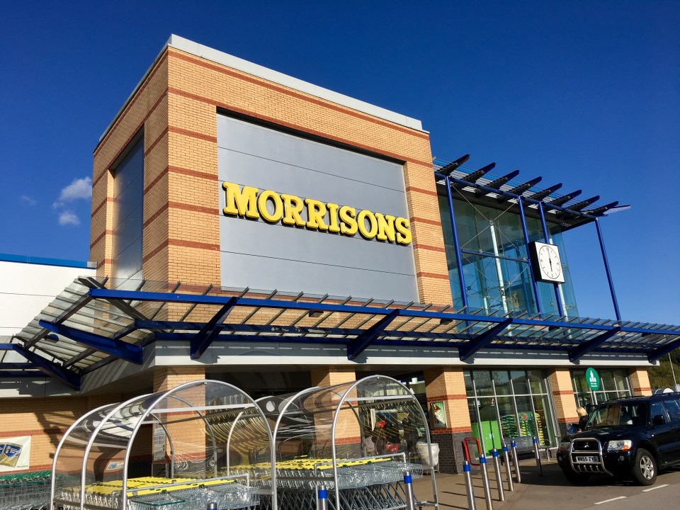 Swansea, UK: April 30, 2018: Main entrance to a Morrisons superstore. Morrisons is the fourth largest chain of supermarkets in the United Kingdom. With trolleys and a blue sky background.