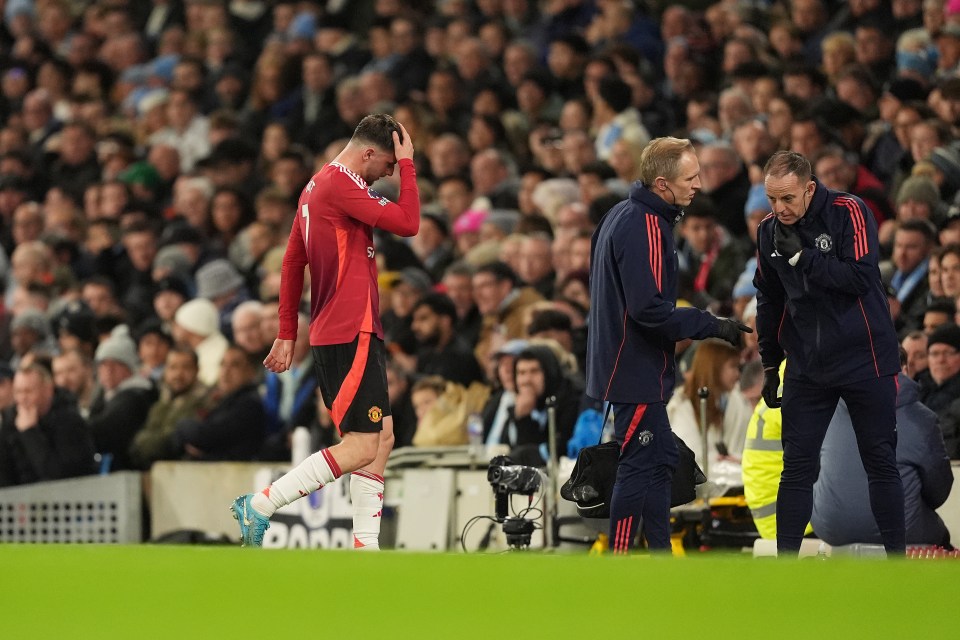 Injured Manchester United's Mason Mount leaves the pitch, assisted by medical staff.