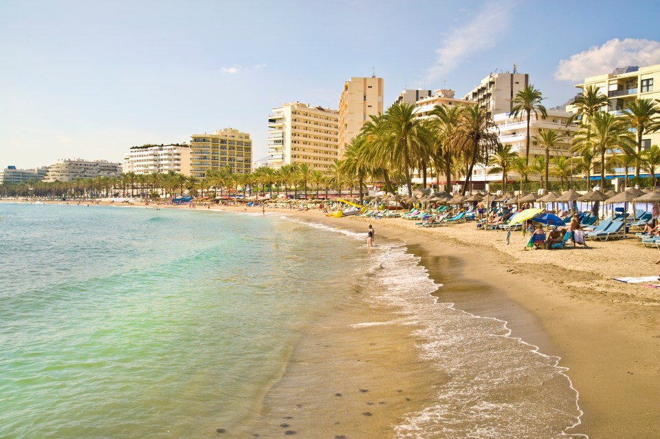 Beach in Marbella, Spain, with hotels and palm trees.