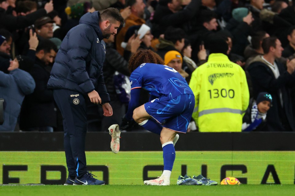 Marc Cucurella of Chelsea changes his boots on the touchline.