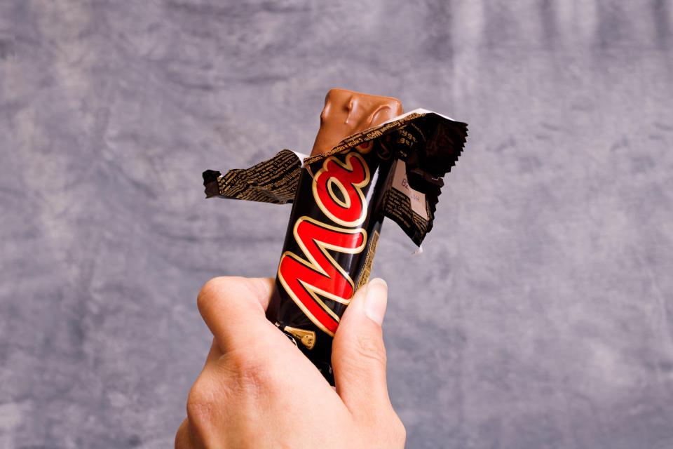 Hand holding an unwrapped Mars chocolate bar.