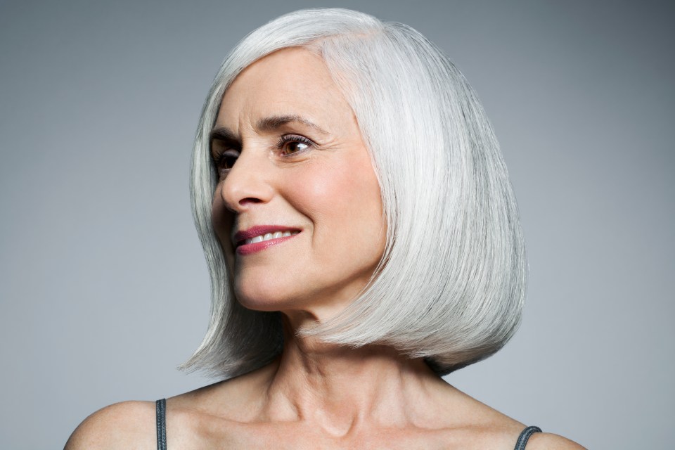 Smiling mature woman with shoulder-length gray hair.