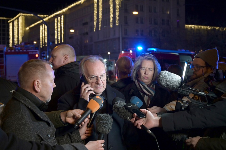 Minister-President of Saxony-Anhalt giving a statement to reporters at a Christmas market.