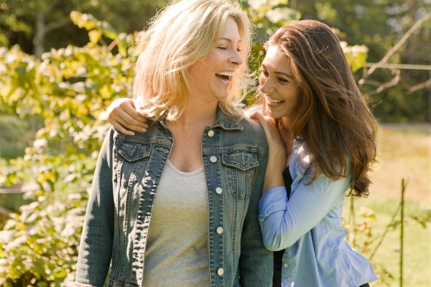 A mother and daughter laughing and walking together outdoors.