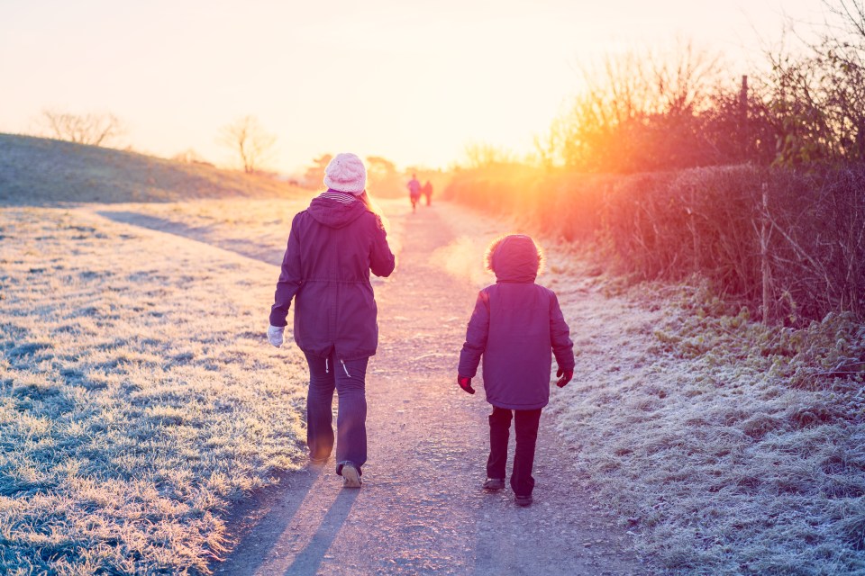 Mother and son walking to school on a frosty path.