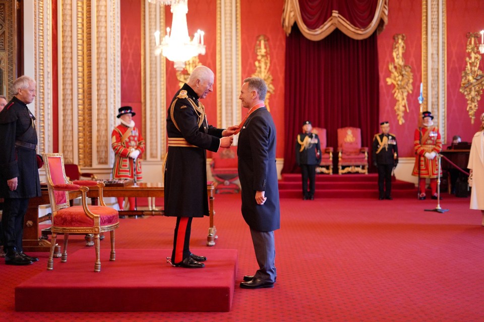 King Charles III bestowing an honor on Christian Horner at Buckingham Palace.