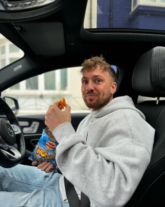 Man in a car eating crisps.